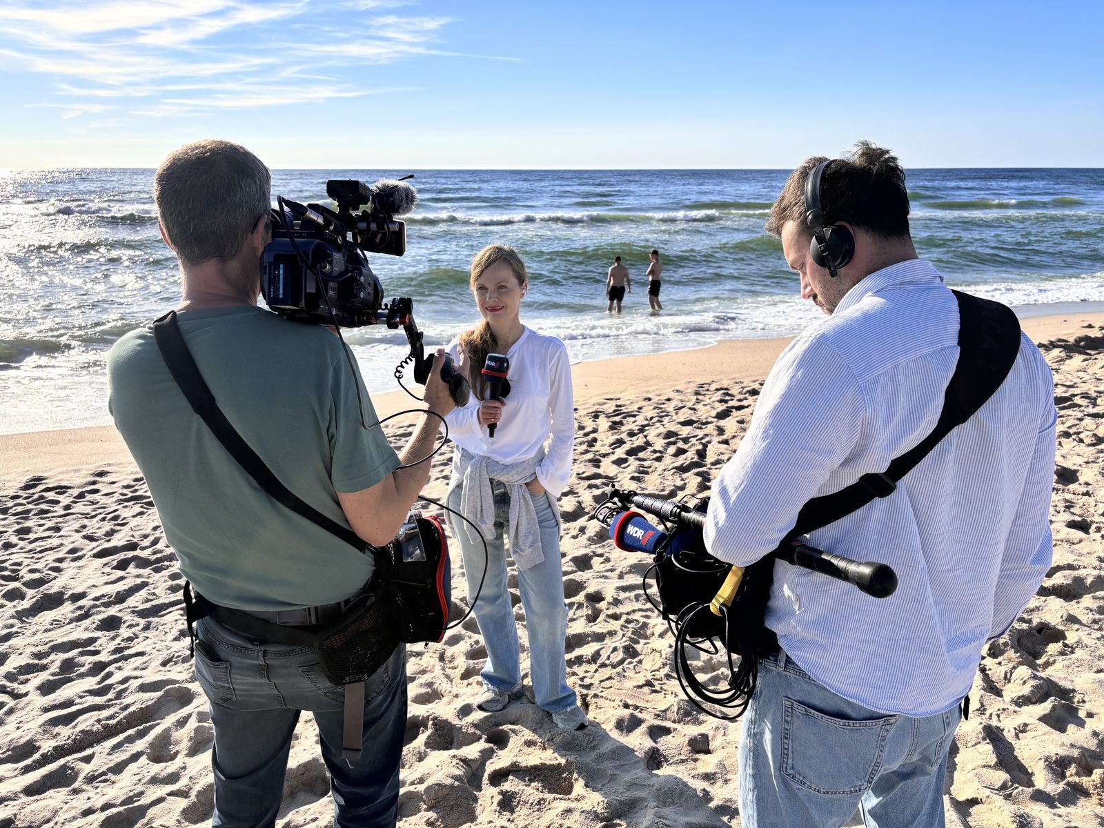 Astrid Houben mit WDR-Mikrofon am Strand von Sylt, Kamera und Ton im Vordergrund